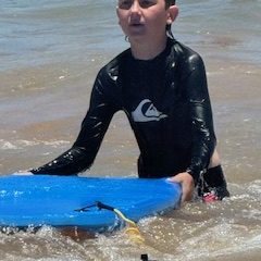 a person in a wet suit on a beach near a body of water